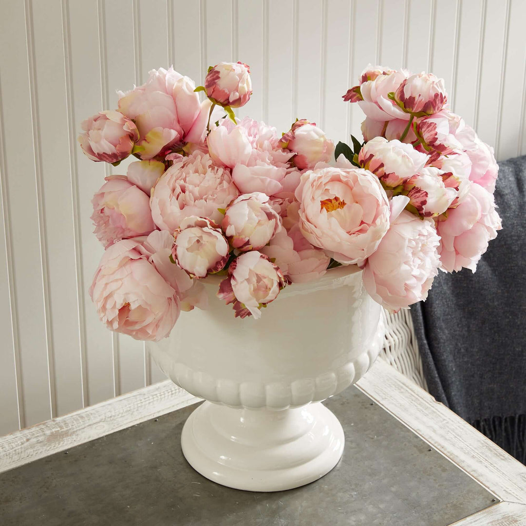 White ceramic urn planter filled with pink peonies, perfect for Tuscan-inspired decor.