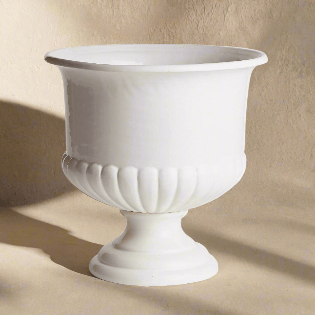 White ceramic urn planter with flared rim and pedestal base for Tuscan-inspired decor.