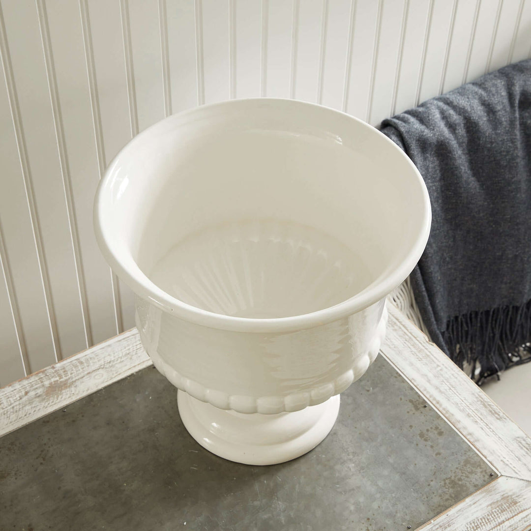 White ceramic urn planter with flared rim and pedestal base, ideal for Tuscan-inspired decor.