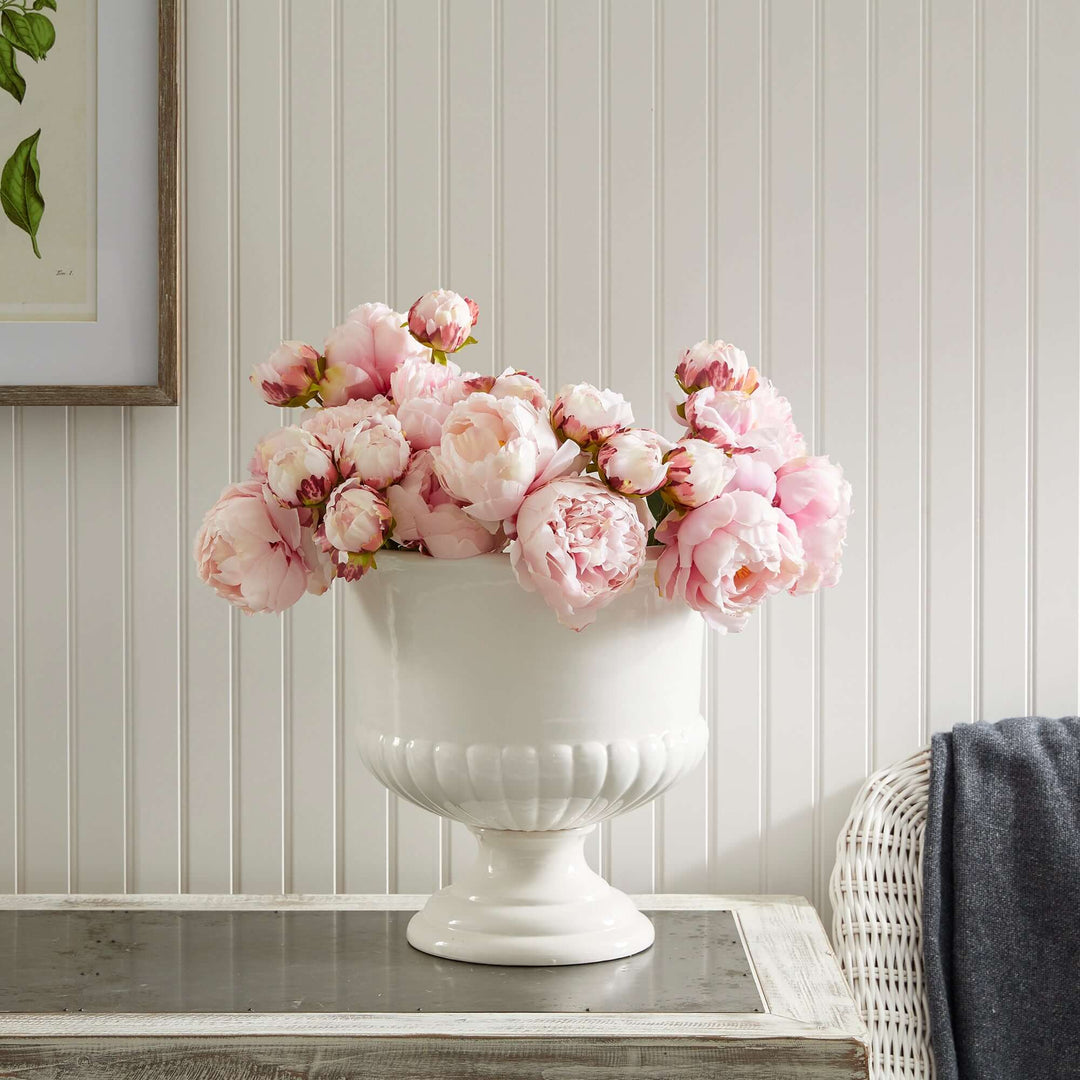 White ceramic urn planter with pink peonies, enhancing Tuscan-inspired decor and adding elegance to any interior.
