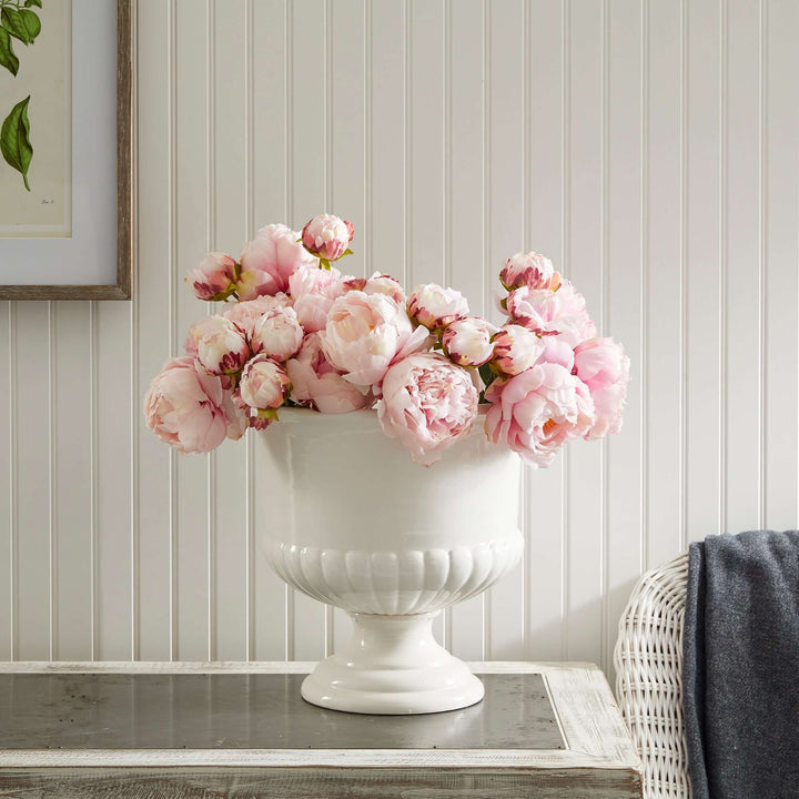 White ceramic urn planter with pink peonies, enhancing Tuscan-inspired decor and adding elegance to any interior.