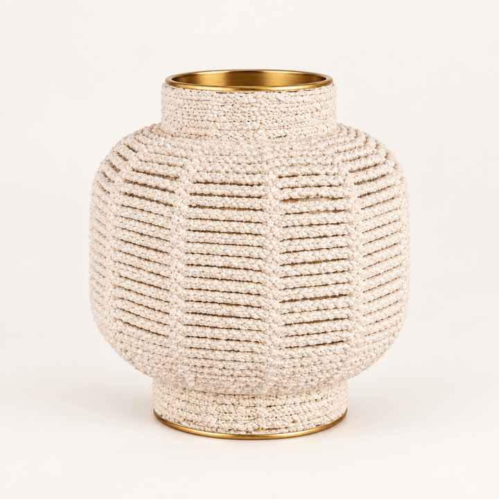 White macrame brass-finish vase on a warm white studio background
