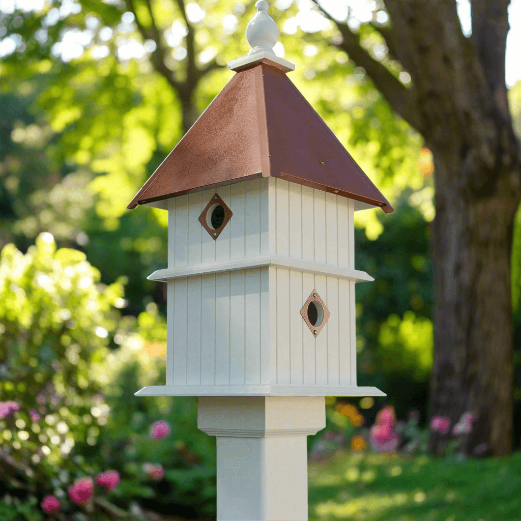 White Two Story Birdhouse with Copper Roof in a garden setting.