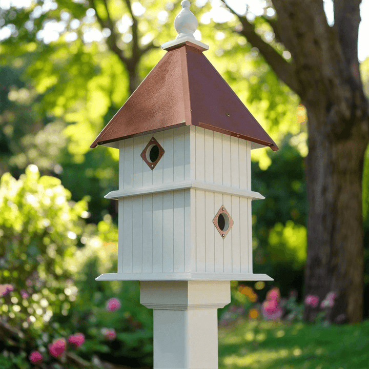 White Two Story Birdhouse with Copper Roof in a garden setting.