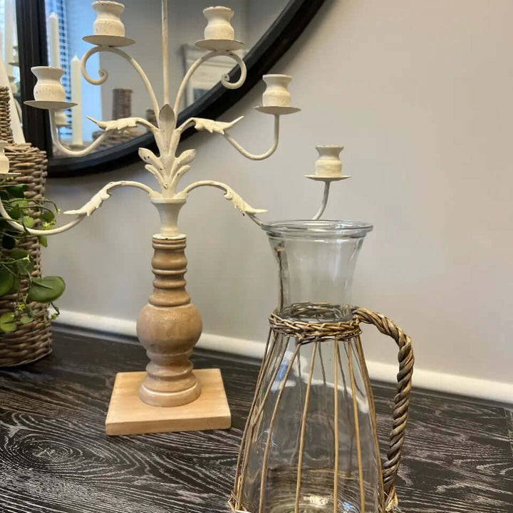 Willow-wrapped glass pitcher beside a candleholder