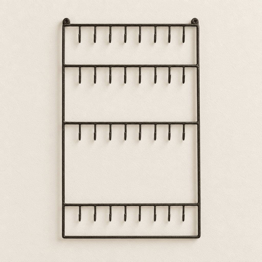Dark wire wall jewelry organizer on an off-white wall.