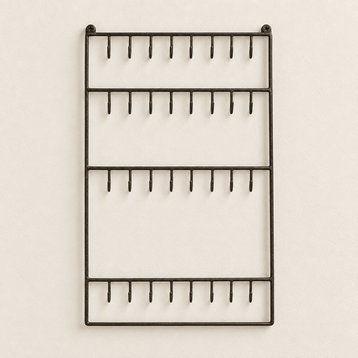 Dark wire wall jewelry organizer on an off-white wall.