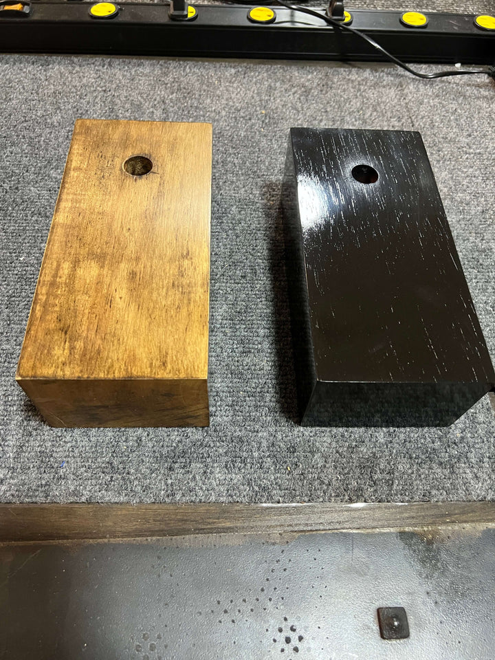 Comparison of two wooden blocks on a workbench with different finishes and drilled holes