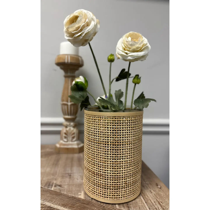 Large woven rattan glass vase holding white flowers