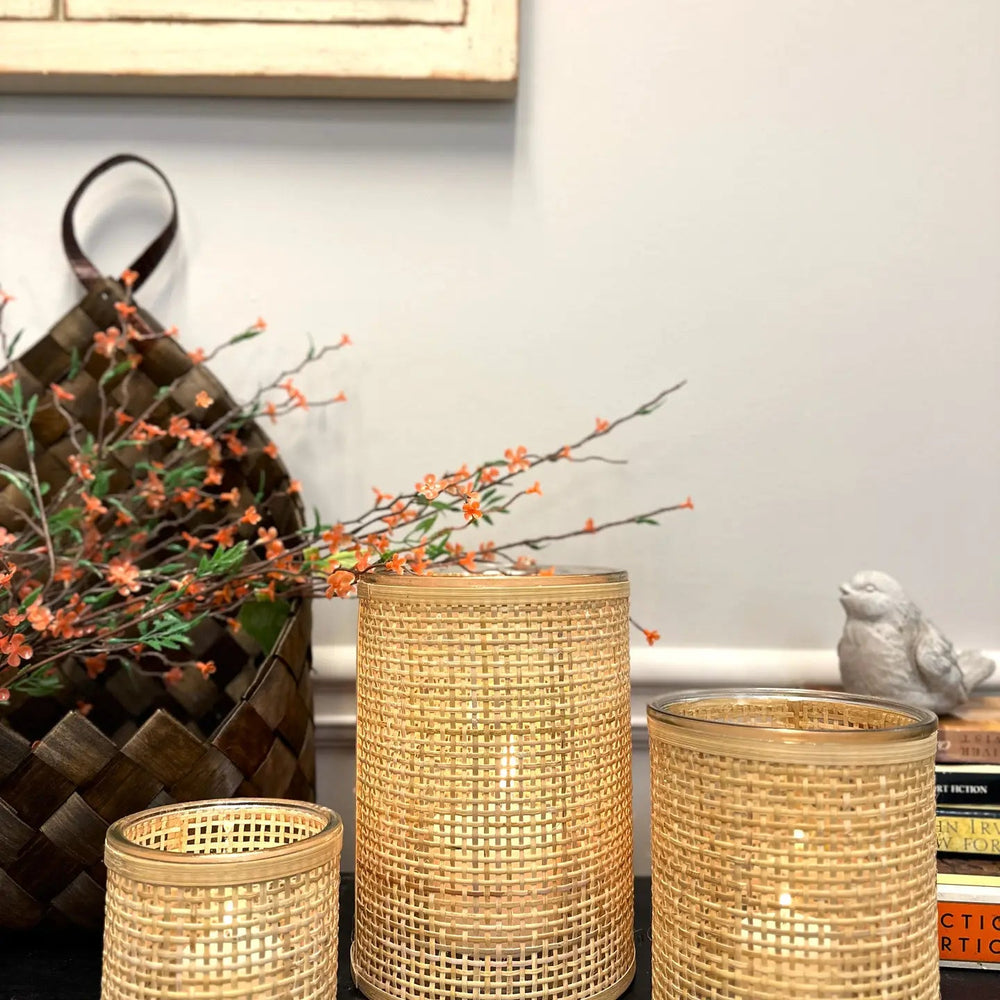 Three rattan-wrapped glass vessel sizes glowing with candles
