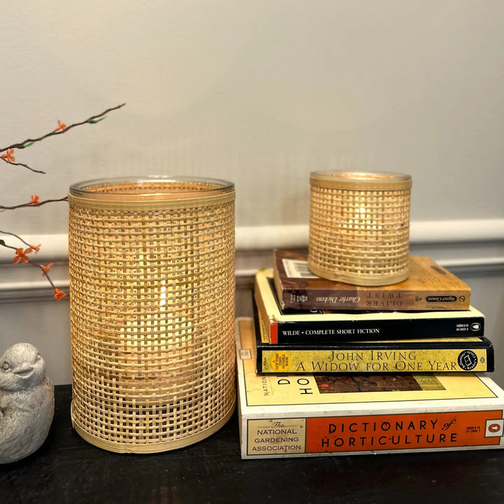 Rattan-wrapped glass candle holders glowing beside stacked books