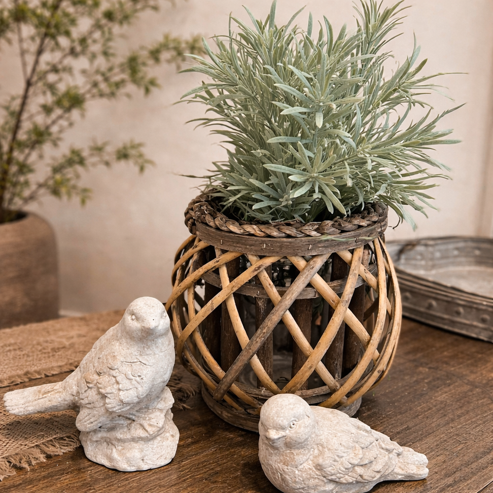 Low woven willow lantern styled with greenery beside bird ornaments
